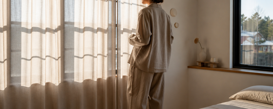 Linen pajama set laid on a bed in a bright bedroom