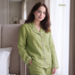 A woman wearing a light green pajama set with white piping trim, standing in a softly lit bedroom. The word 'Citron' appears in the top right corner.