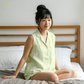 Woman in a light green outfit sitting on a bed with a wooden headboard.