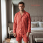 Man wearing coral pajamas standing in a bedroom