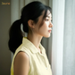 Woman in a yellow shirt standing by a window with light streaming in