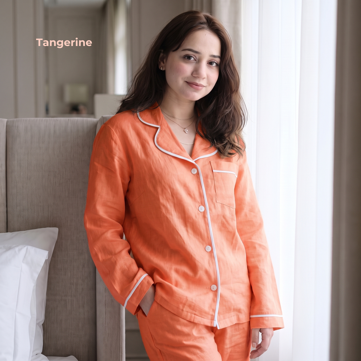 Woman wearing tangerine-colored pajamas with white piping in a bedroom setting.