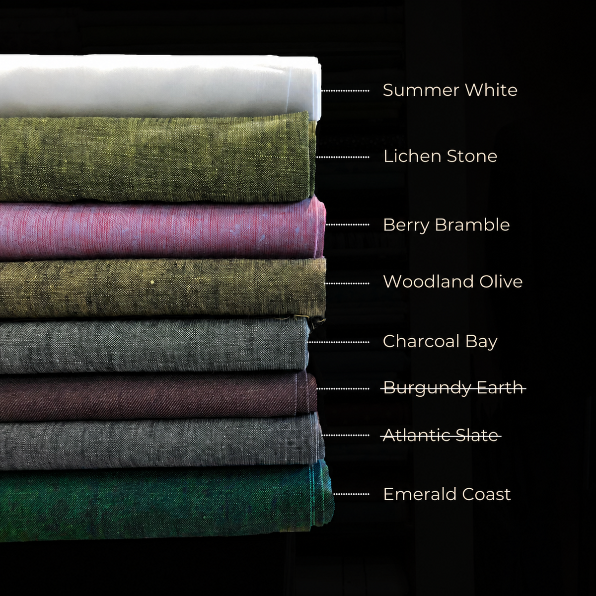 A stack of folded fabric swatches in multiple colors and textures, labeled with names like Summer White, Lichen Stone, Berry Bramble, Woodland Olive, Charcoal Bay, Burgundy Earth, Atlantic Slate, and Emerald Coast on a black background.